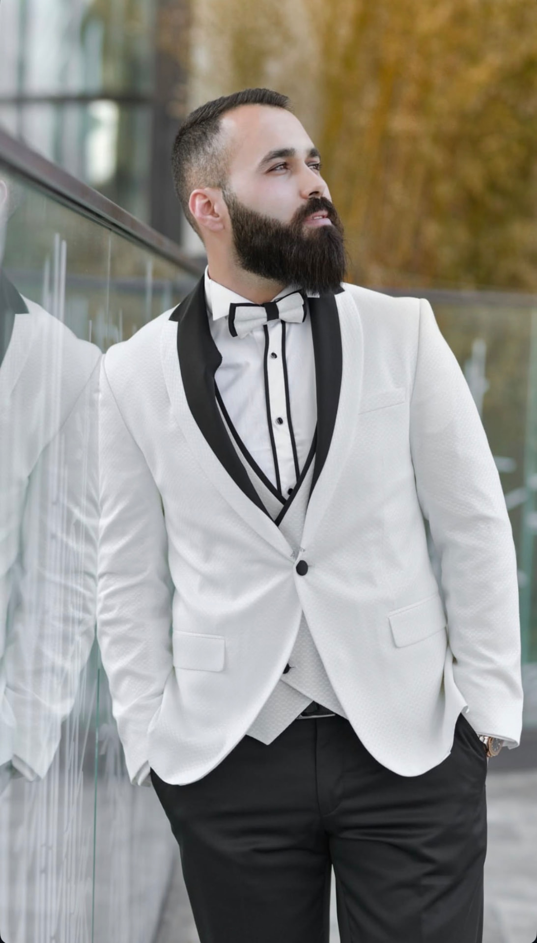 Portrait of the groom in a white tuxedo with a black bow tie