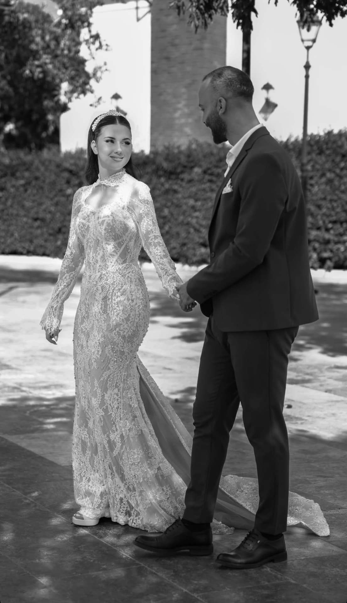 Black and white photograph of a bride and groom holding hands