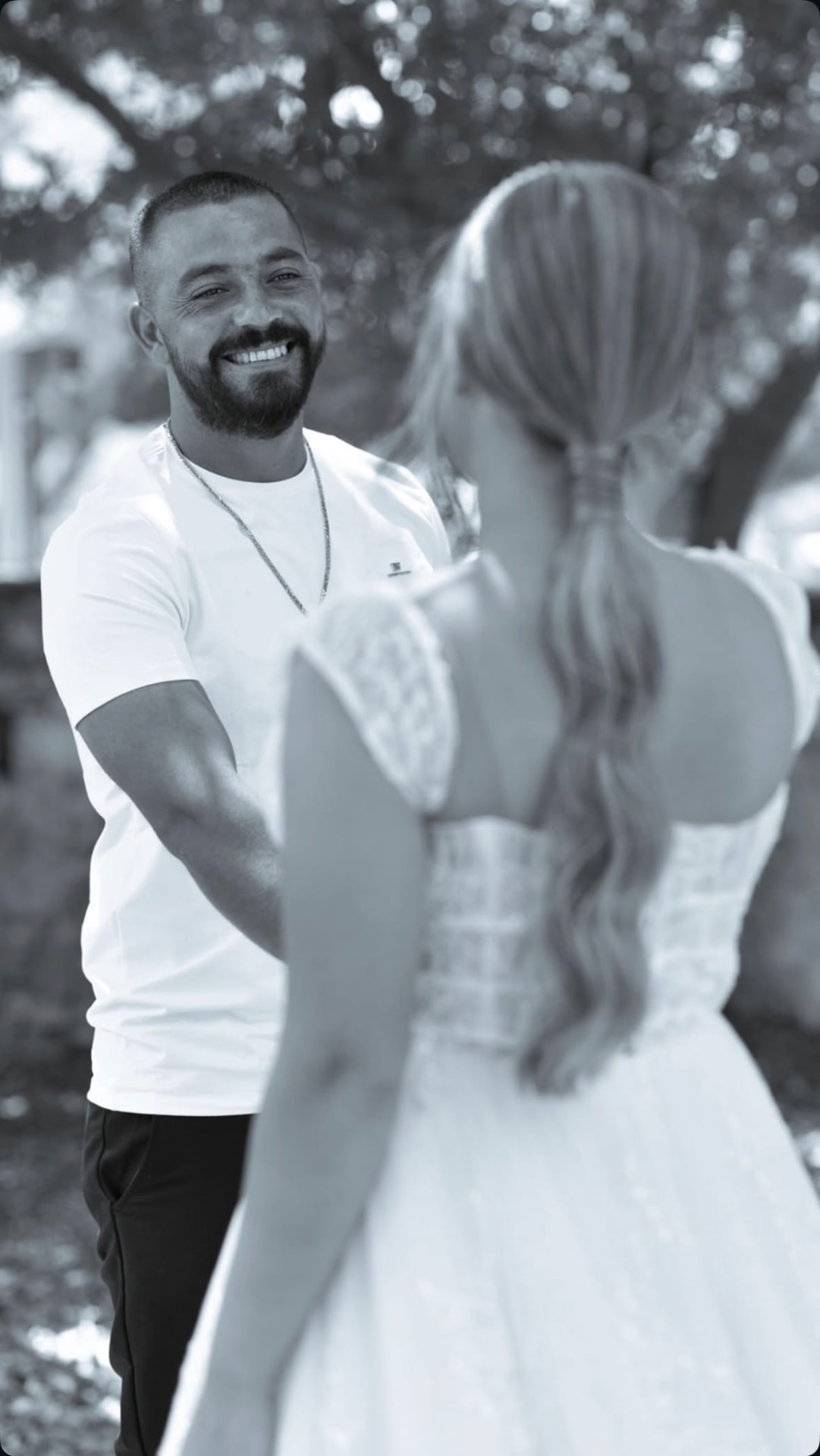 Black and white photograph of the groom smiling at the bride