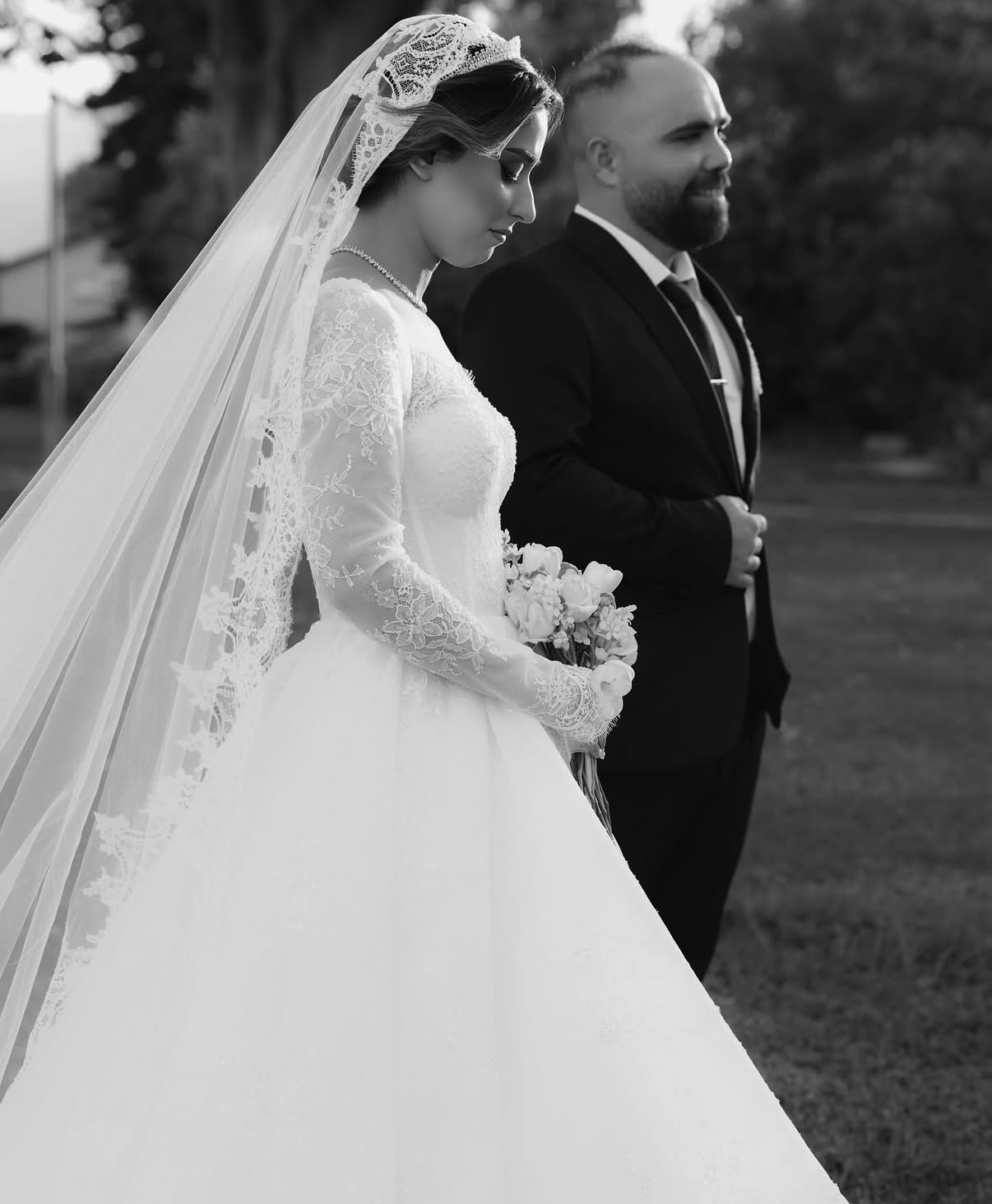 Black and white photograph of the bride in a lace veil beside the groom